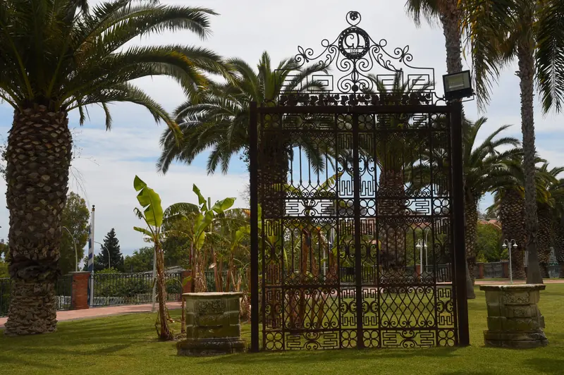 Il cancello in ferro battuto all'ingresso del parco, tra due palme