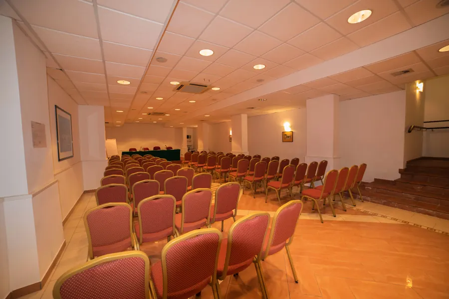La sala riunioni con sedie rosse e tavolo di presidenza